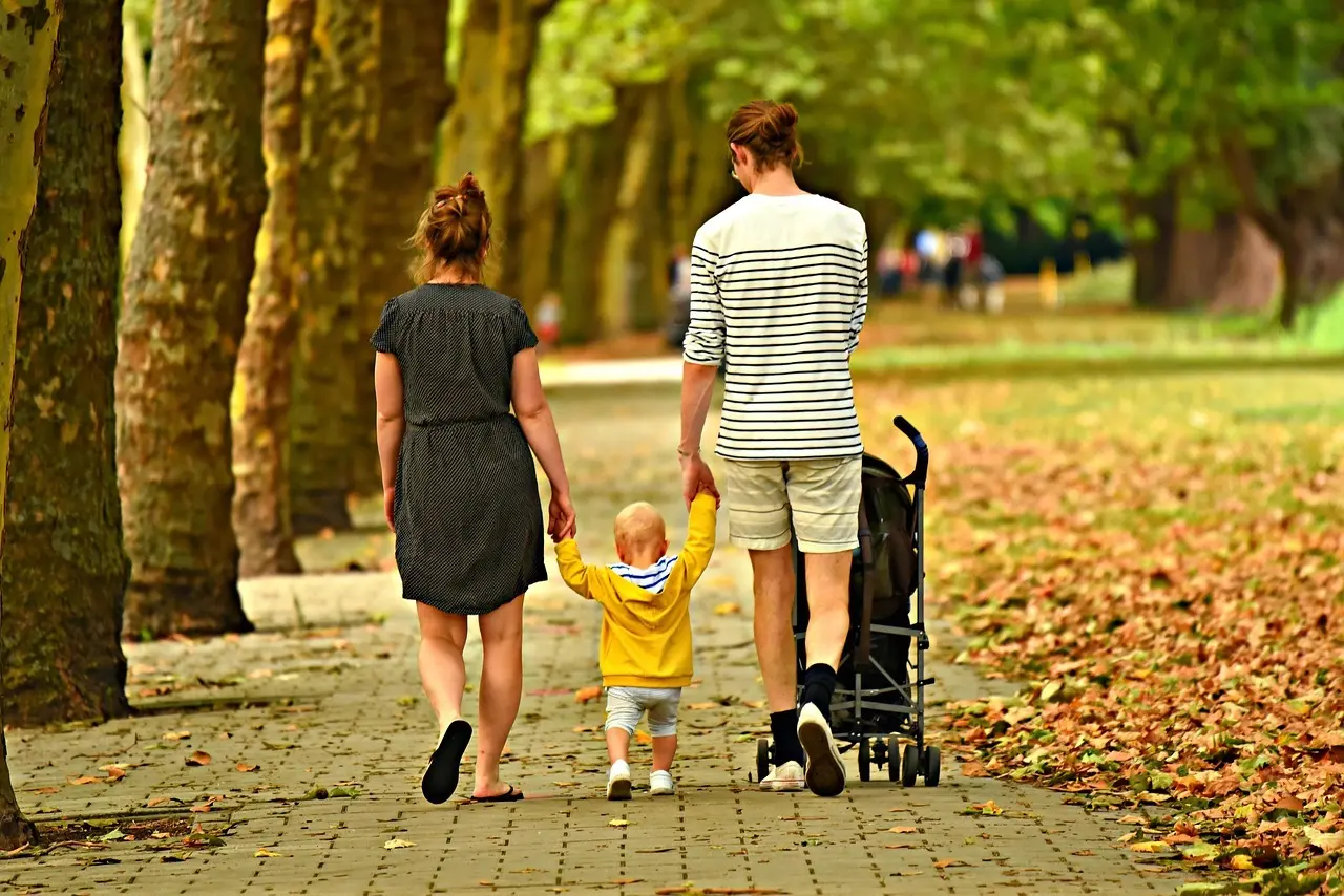 Forældre og et lille barn går hånd i hånd i en park